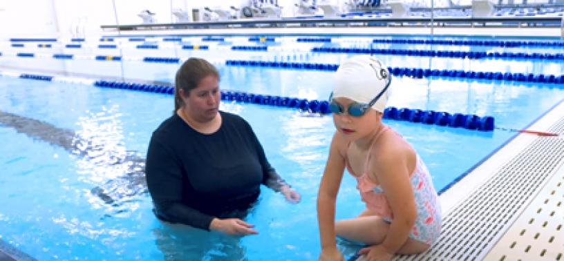 Girl entering the water with her instructor