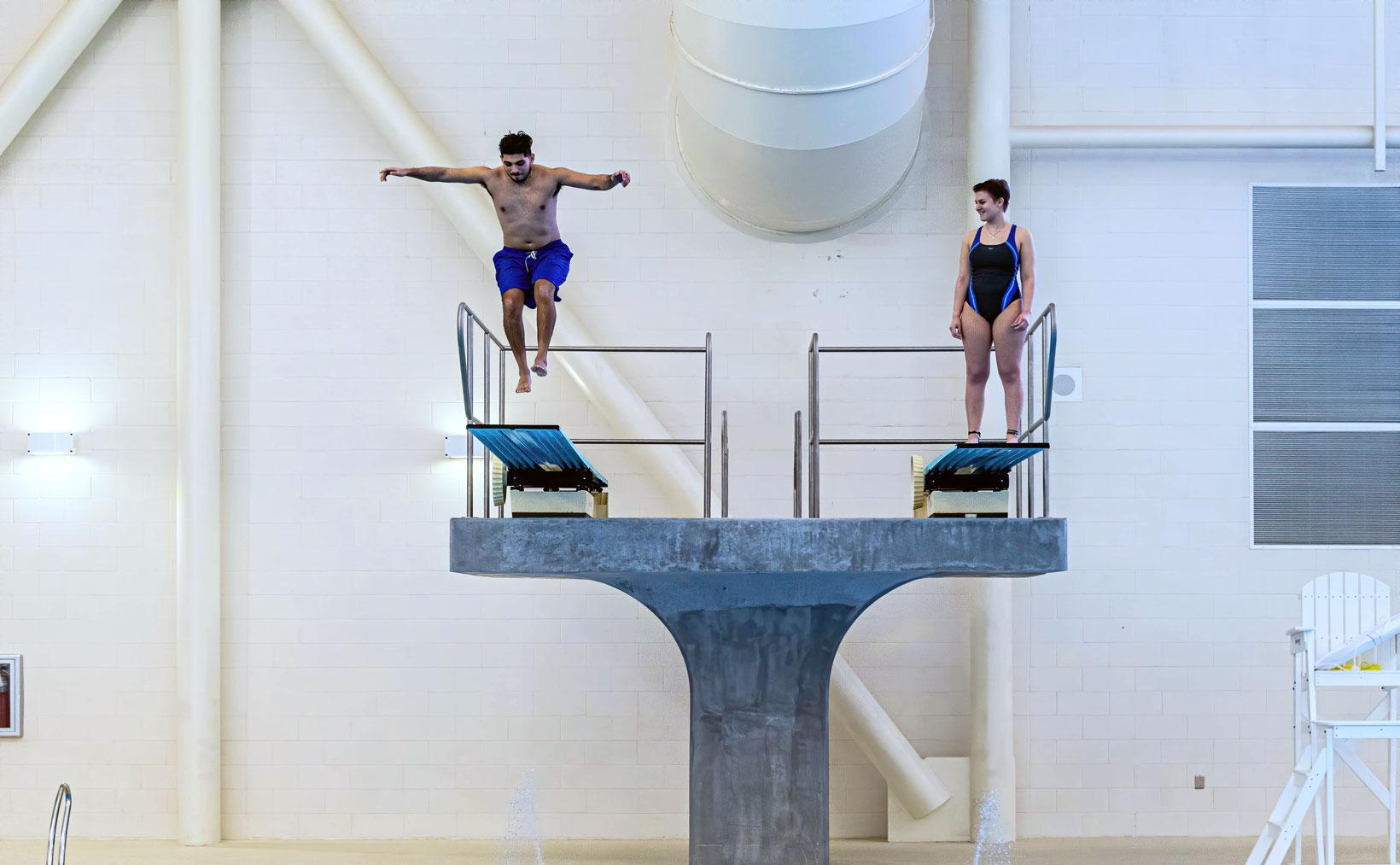 Two divers preparing to jump from the high diving platforms