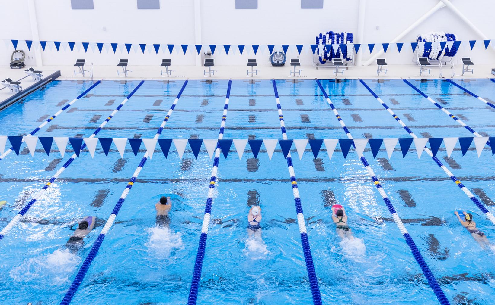 High school swimmers completing laps with boards