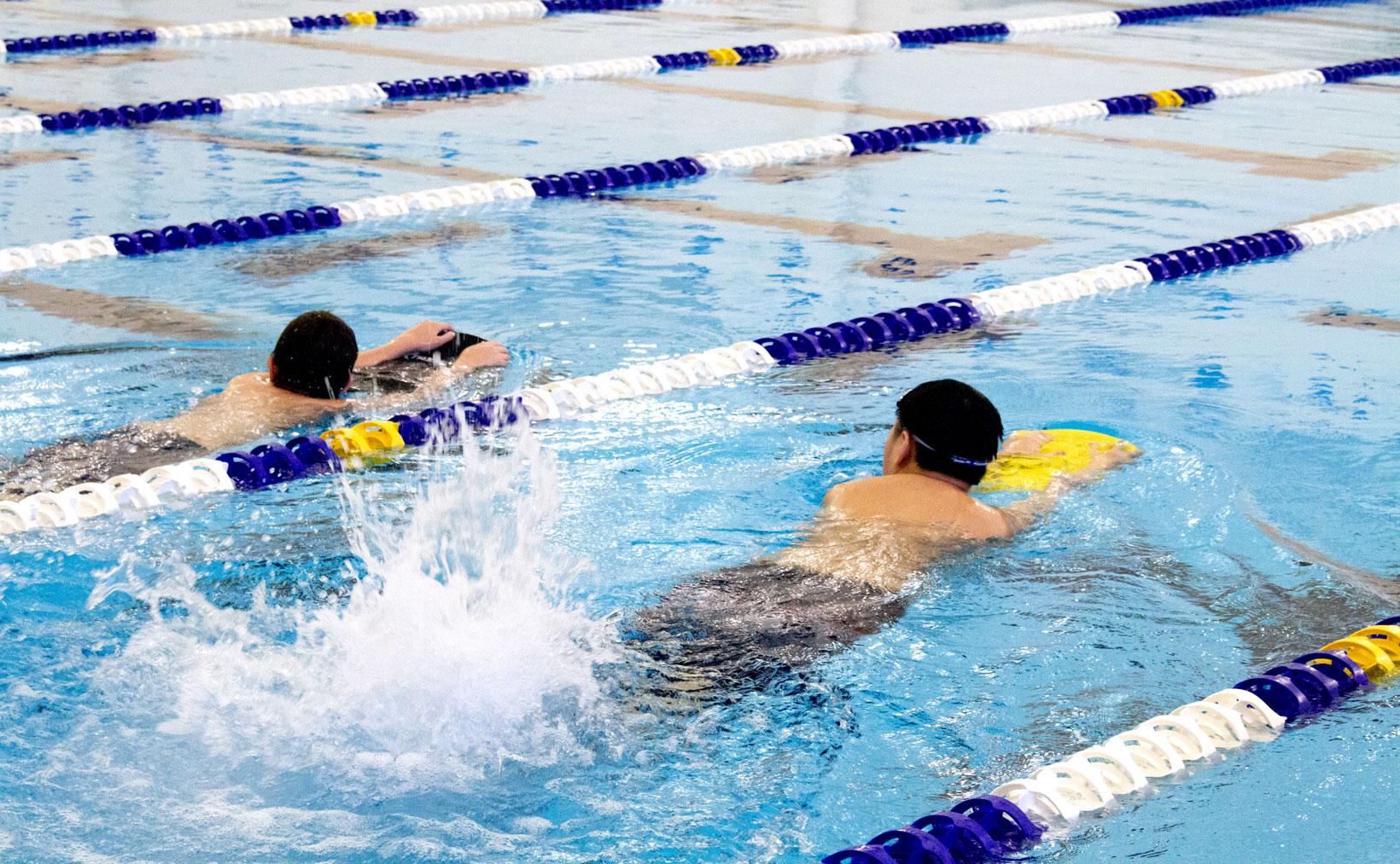 Two boys swimming with boards